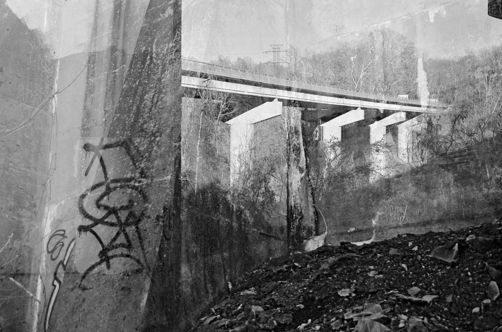 Triple exposure of a highway bridge, graffiti on its concrete pillars, and dirt/trash